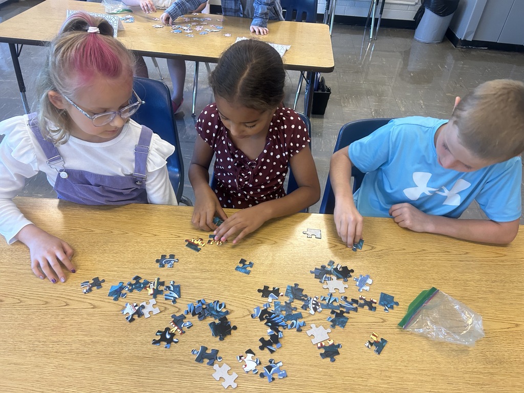 Three young students working a puzzle together.