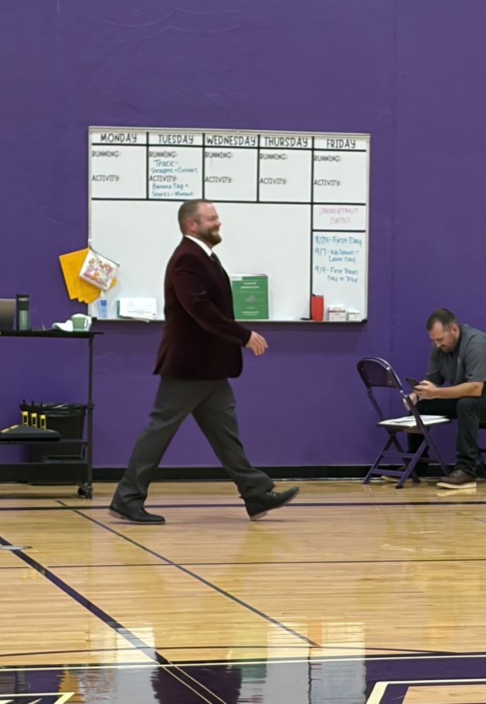 A staff member walking in a purple school gym.