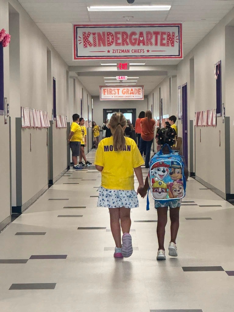 Two students holding hands while walking down a school hallway.