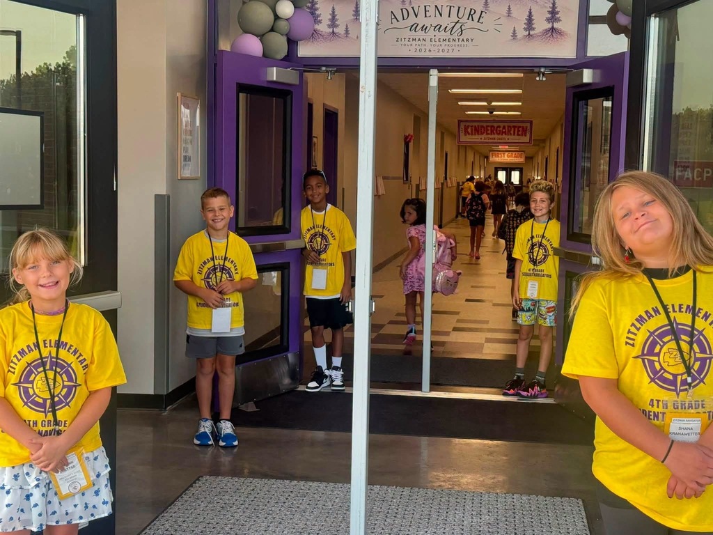 Five students smiling for a photo in a school entryway.