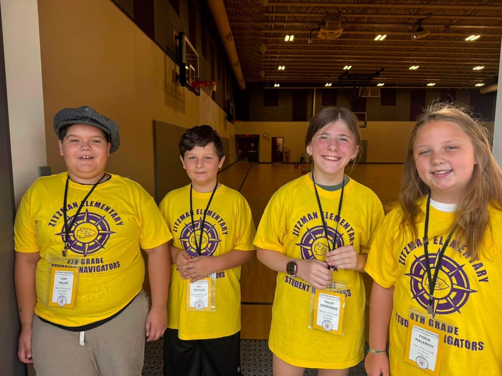 Four students smiling for a photo in a school gym.