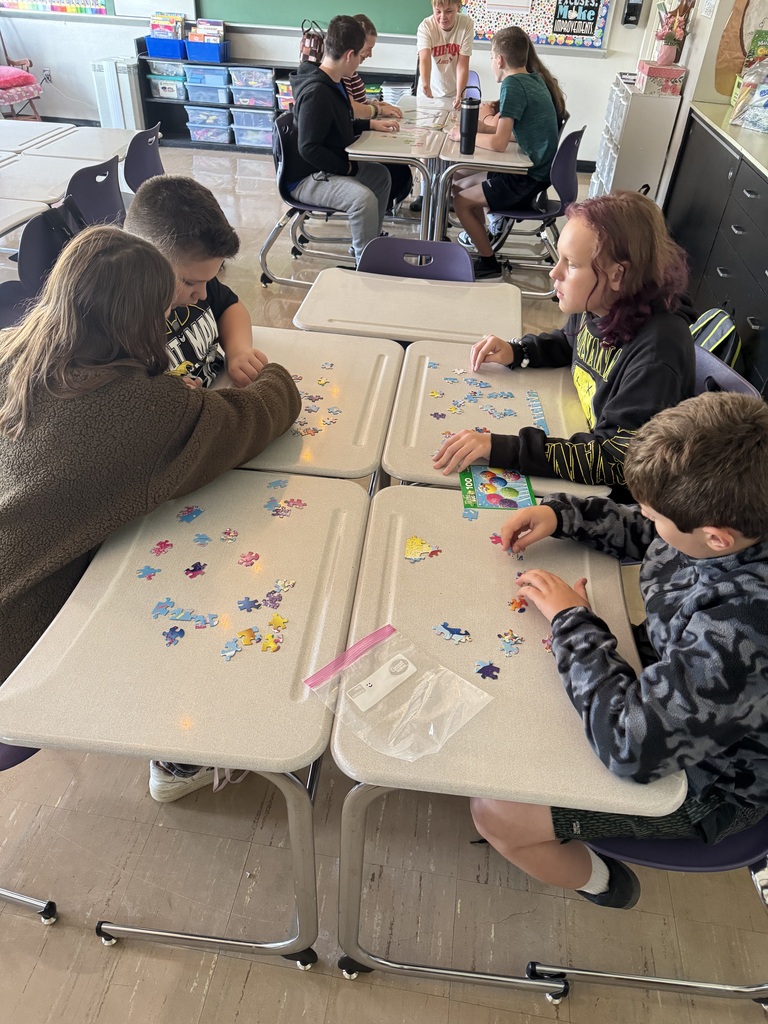 Four students working on a puzzle in a school classroom.