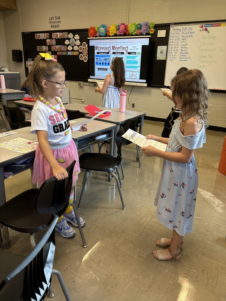 Two students face each other and read from worksheets during a classroom partner activity.