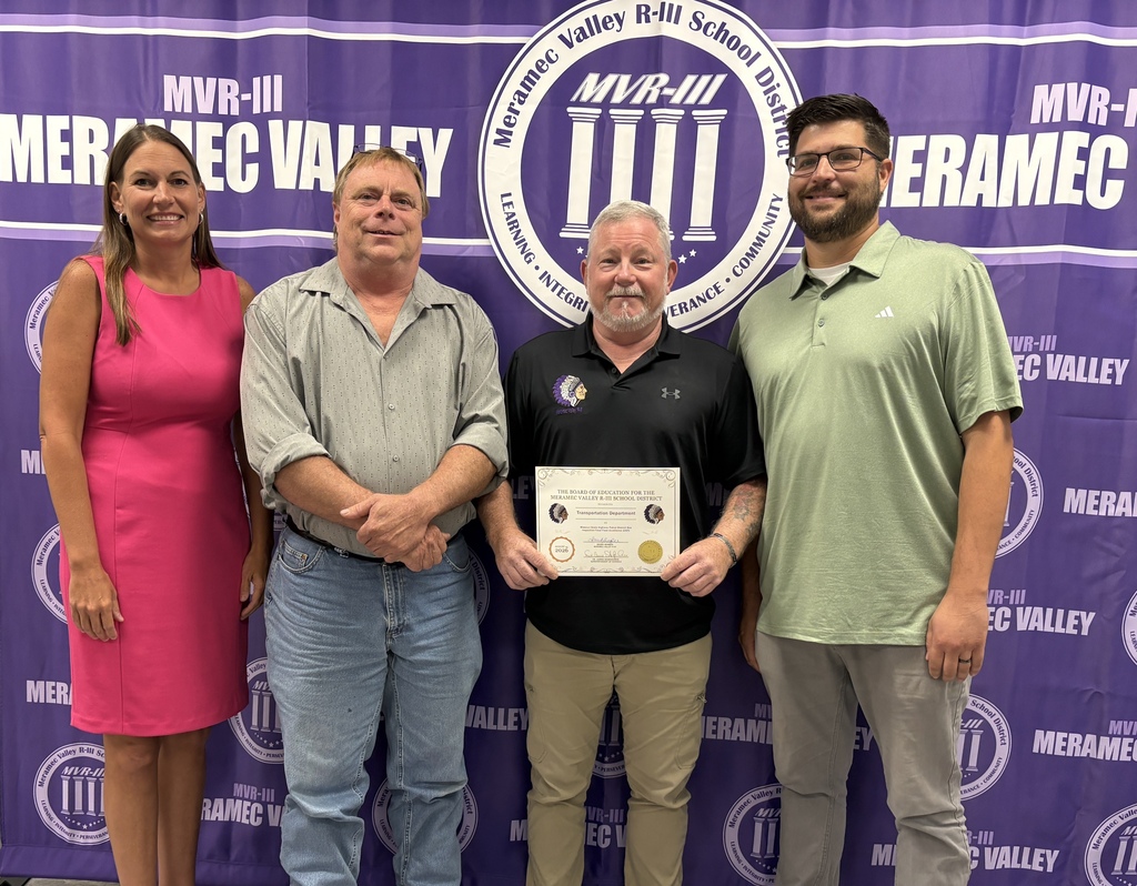 Four adults pose in front of a Meramec Valley R-III backdrop as one holds a Transportation Department recognition certificate.