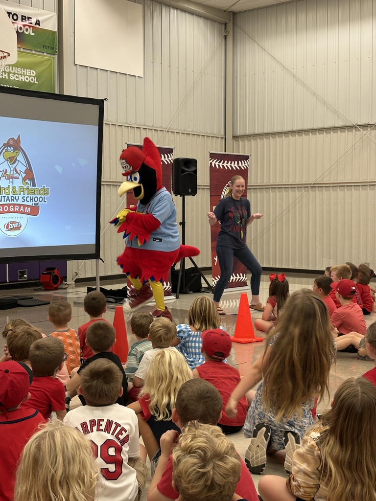 Fredbird and a presenter dance in front of students during the Fredbird & Friends Elementary School Program.