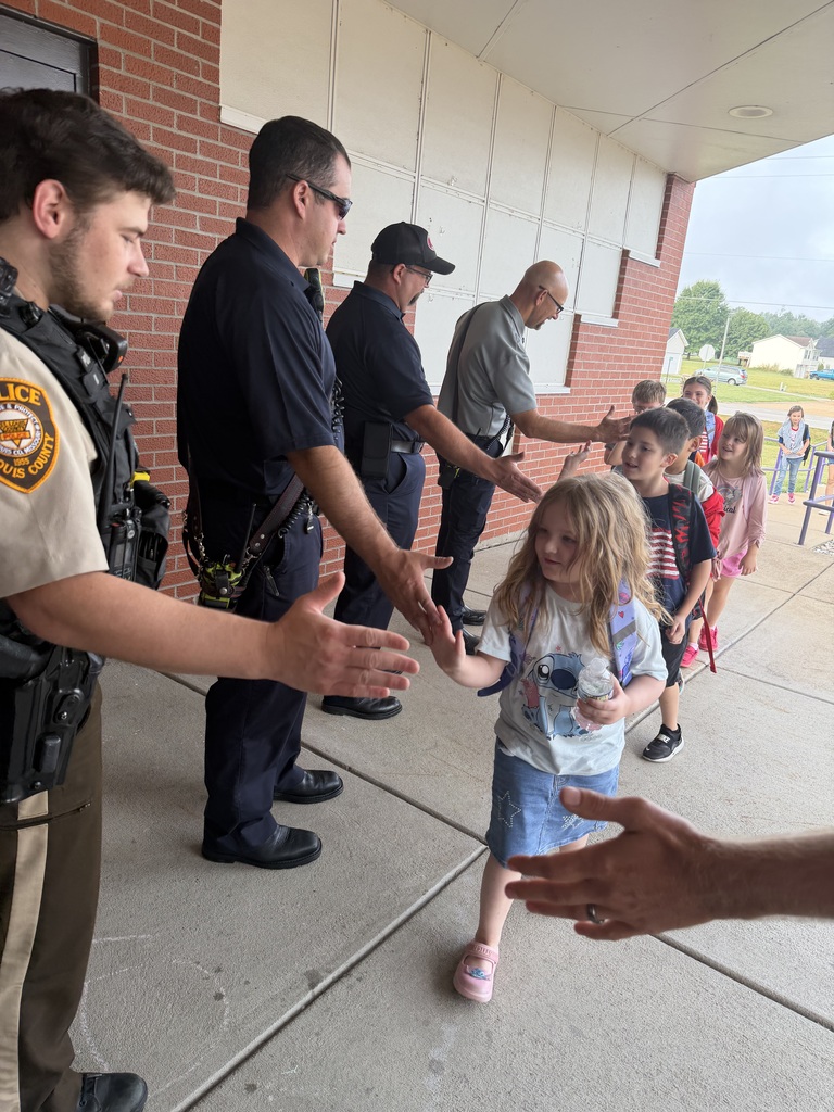 Students exchange high-fives with police officers and first responders while entering school.