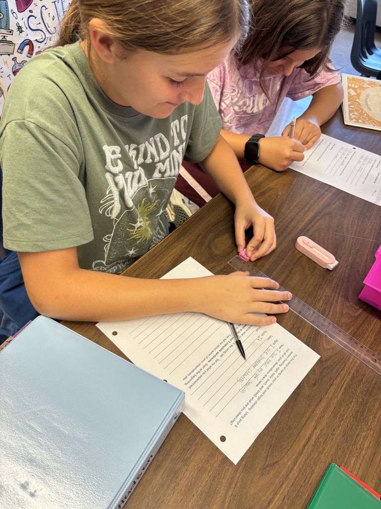 Students conduct a classroom investigation using magnifying glasses, rulers, and worksheets to observe and measure small objects.