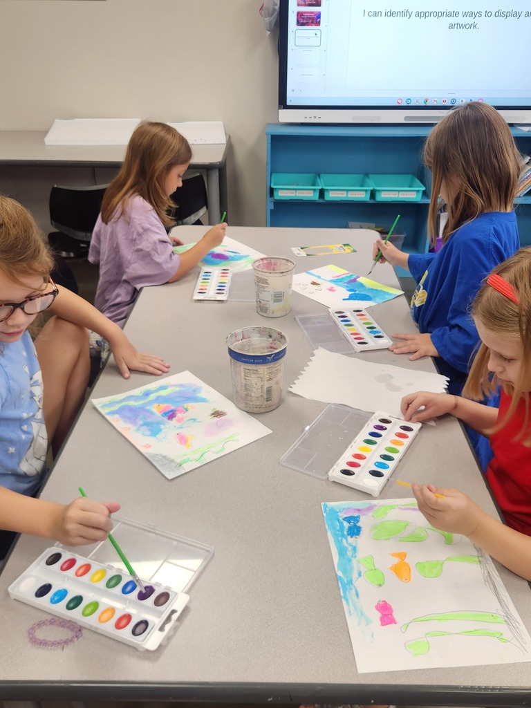 Four students use watercolor paints to create colorful underwater scenes during an art activity.