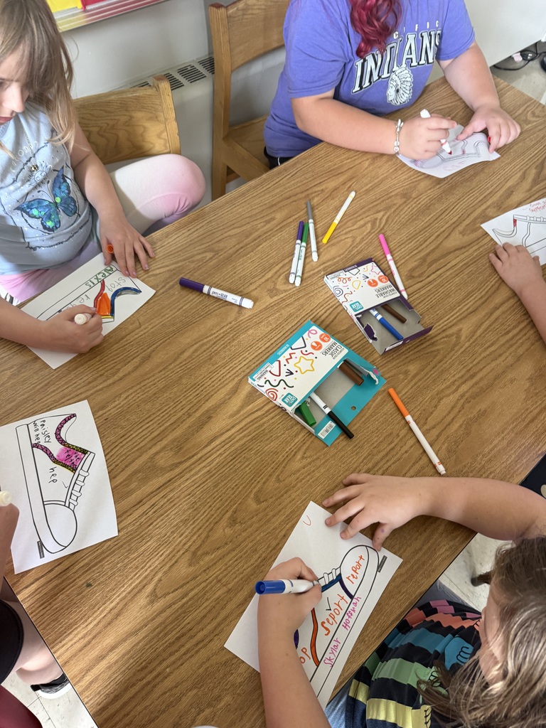 Students working on an art project with markers at a school desk.