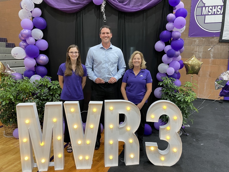 Three adults stand behind a MVR3 lighted sign.