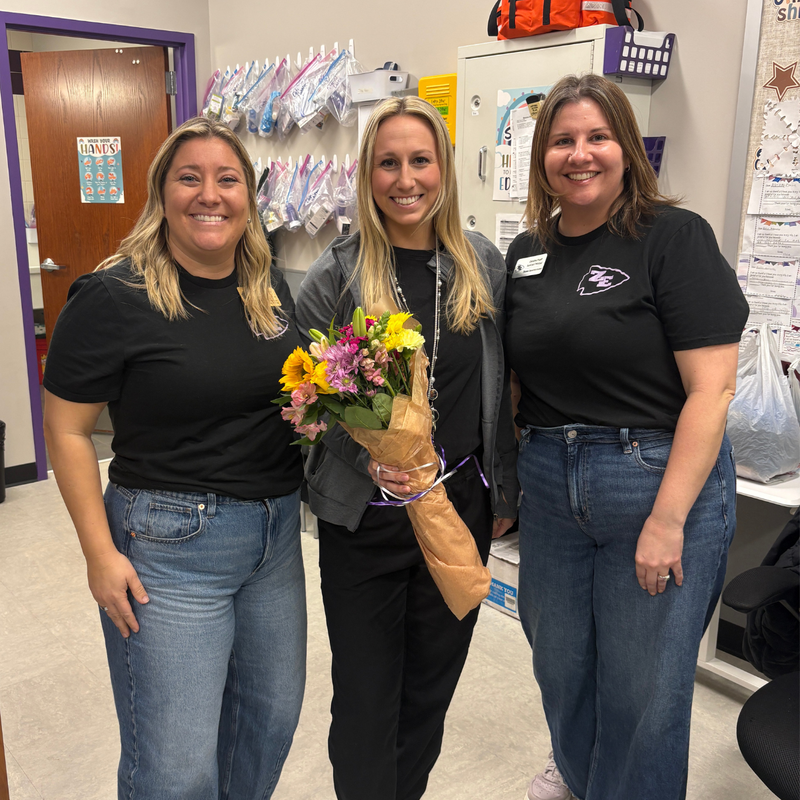 McKenna Ounaian, School Nurse posting with flowers in a group photo.