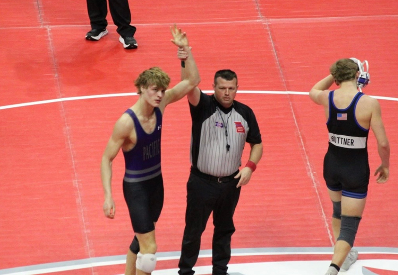 Boys wrestling winning match with arms up.