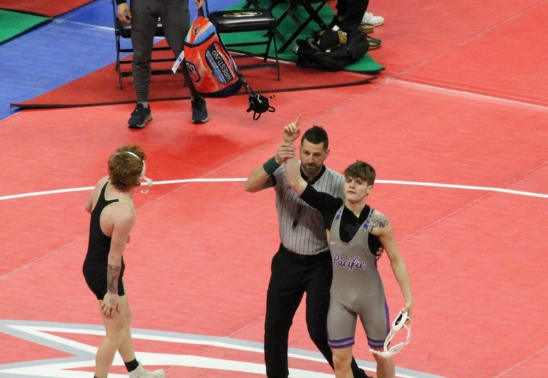 Boys wrestling winning match with arms up.