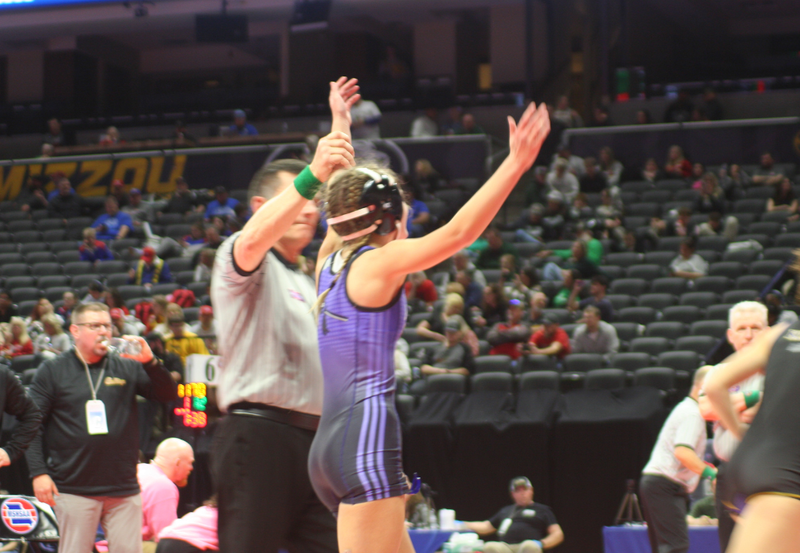 Girls wrestling winning match with arms up.