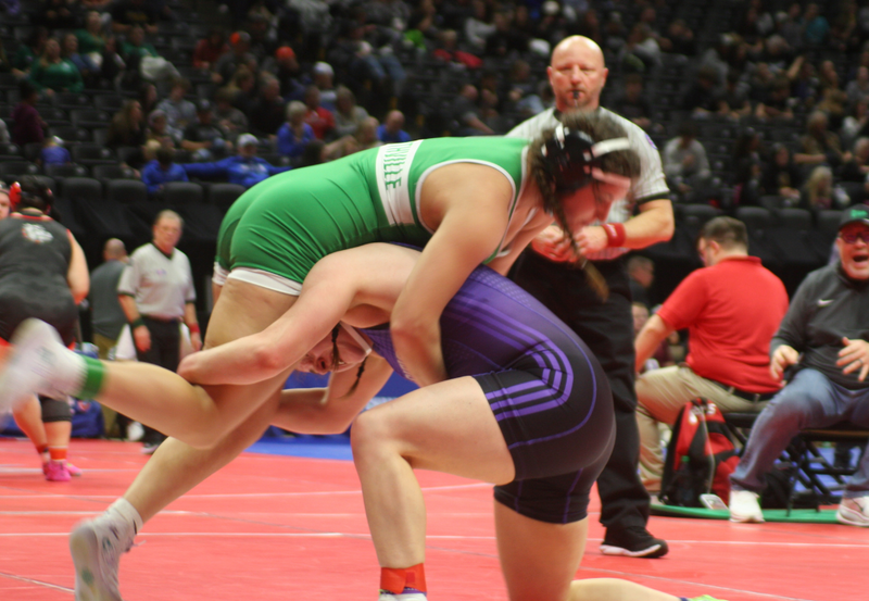 Girls wrestling match with green and purple attire.