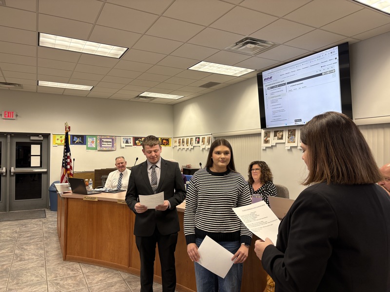 Two students being sworn into office in board of education room.