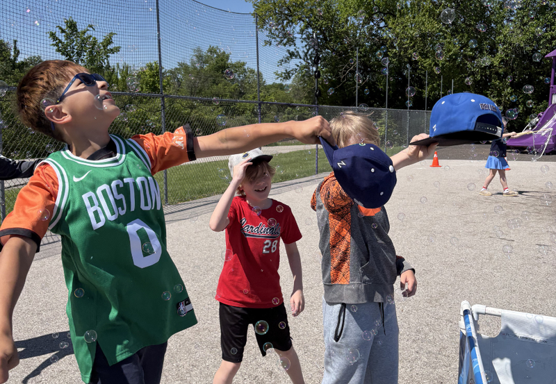 Three students playing with bubbles outside.