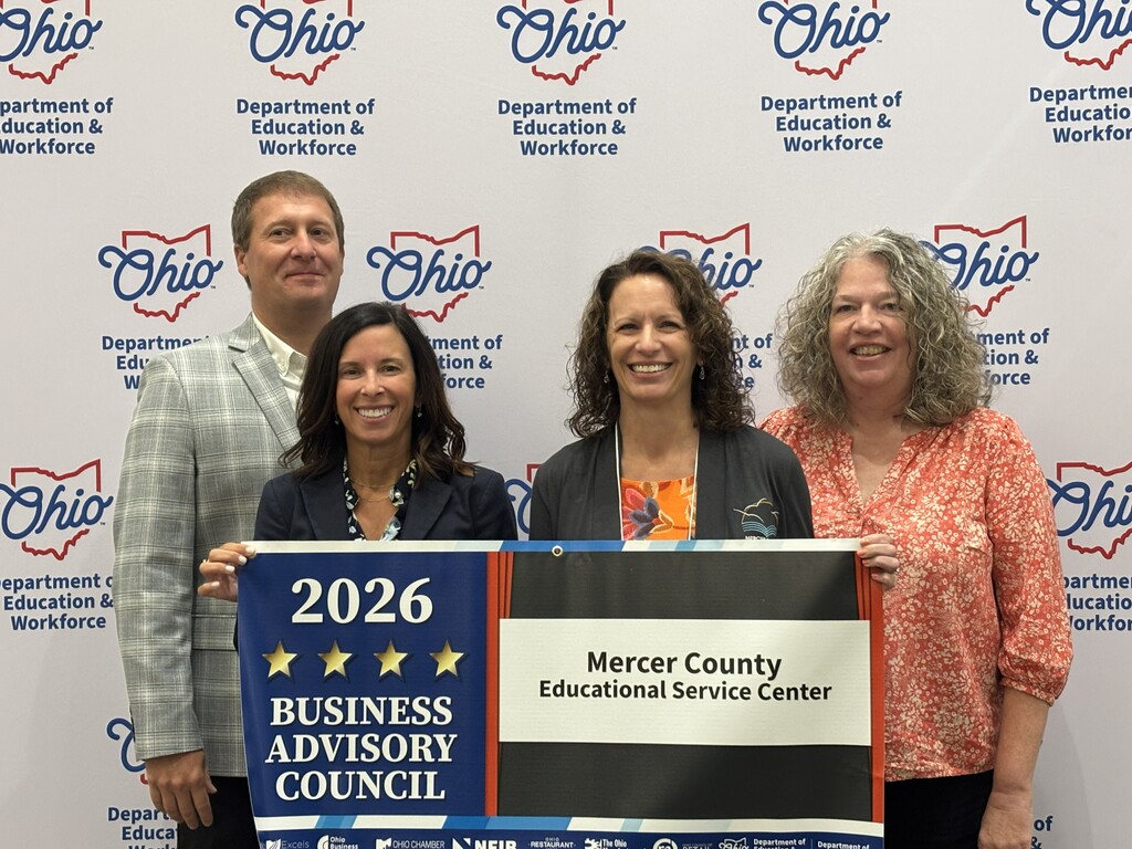 Four people stand next to each other with one holding a sign that reads "2026 BUSINESS ADVISORY COUNCIL".