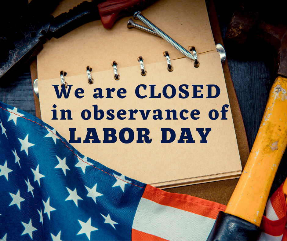 A notebook with "We are CLOSED in observance of LABOR DAY" sits on a wooden surface. Beside it are a hammer, an American flag, and a pair of pliers.