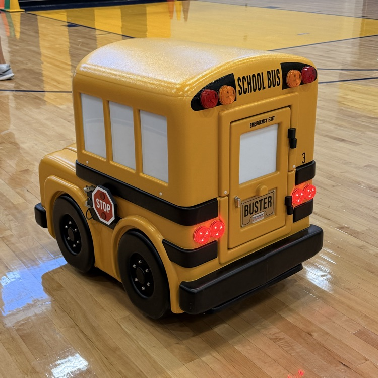 The back of the electronic yellow bus with a license plate that says Buster. 