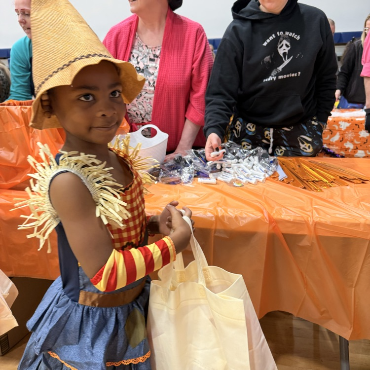 Little girl with dark hair dressed as a scarecrow trick or treating in the gym. 