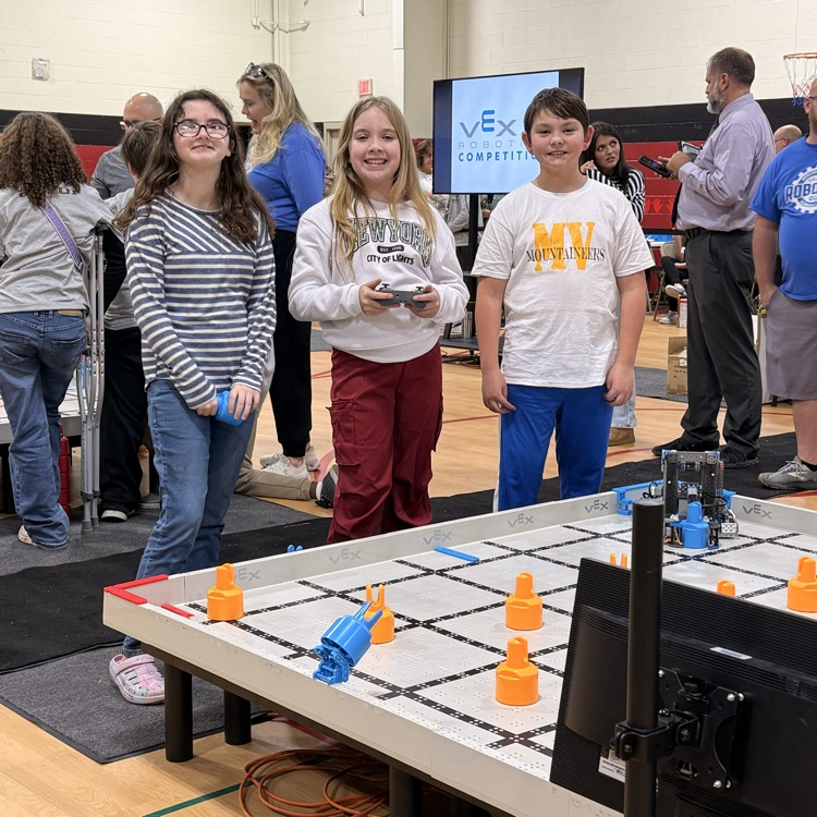 3 students at their robotics table getting ready to compete  