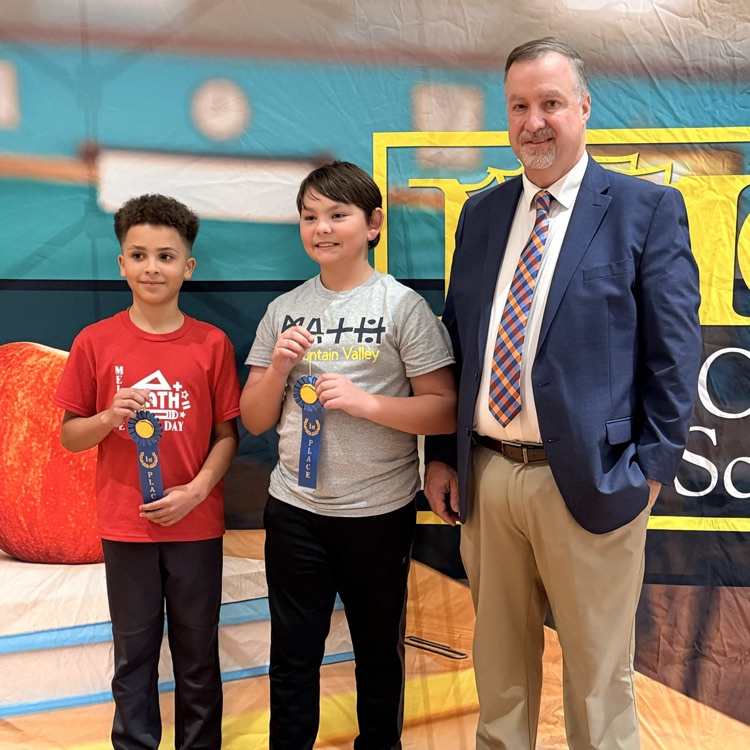a young man in a red shirt and young man in gray shirt holding first place ribbon  