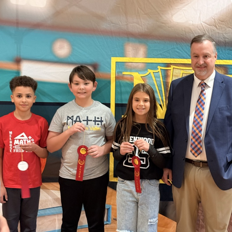 3 students holding red 2nd place ribbons standing beside a man in a suit  