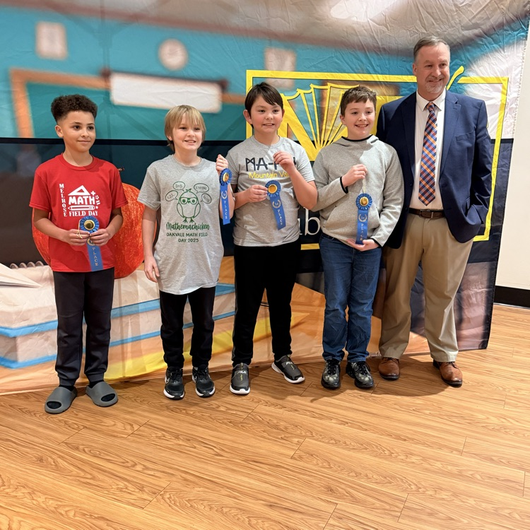 Four young boys holding a blue ribbon standing beside a man in a suit. 