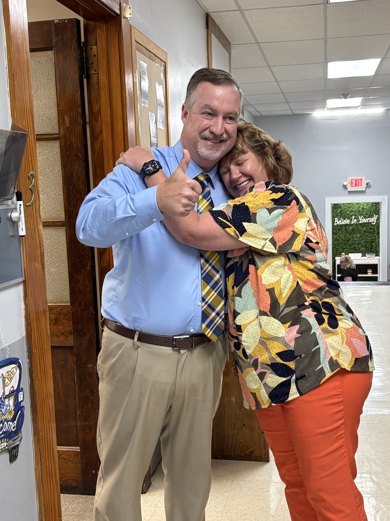 Mrs. Boothe is hugging Dr. Adkins and he is showing a "thumbs up" sign.