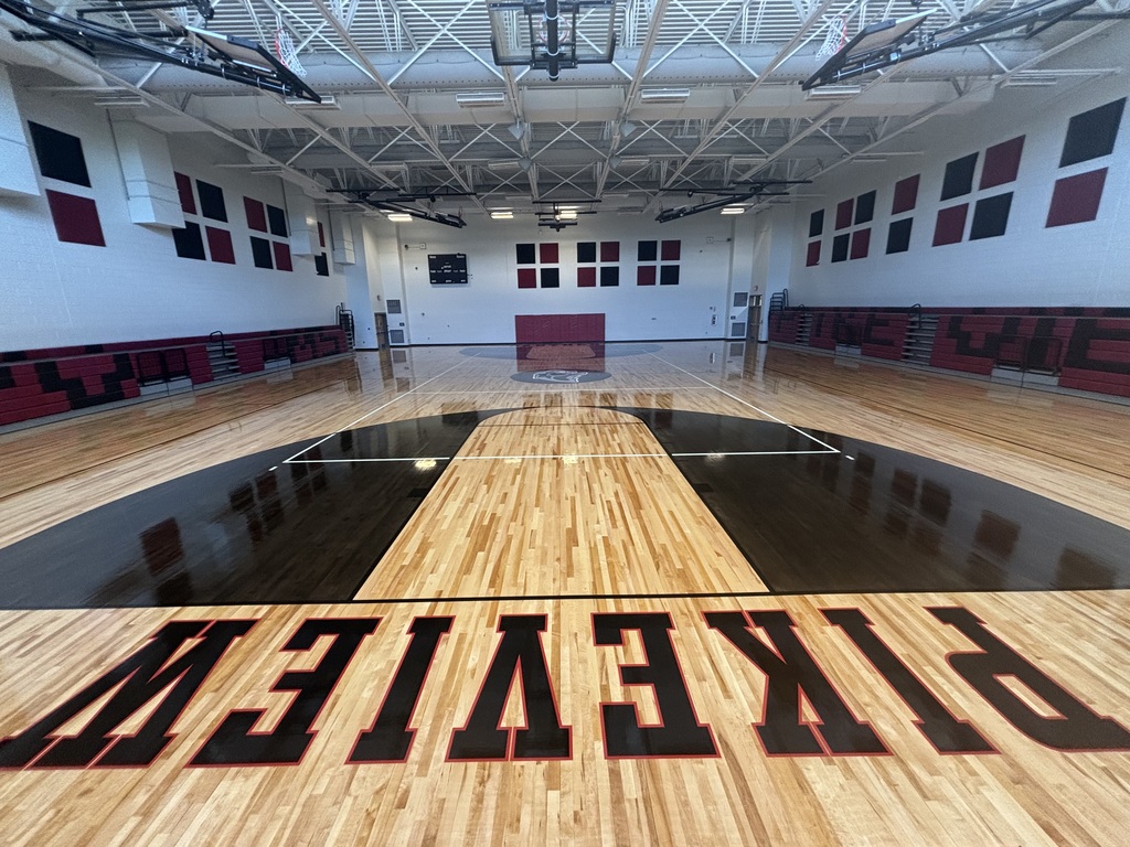 An empty indoor basketball court with polished wooden flooring, featuring red and black markings and the word "Breckenridge" in red.