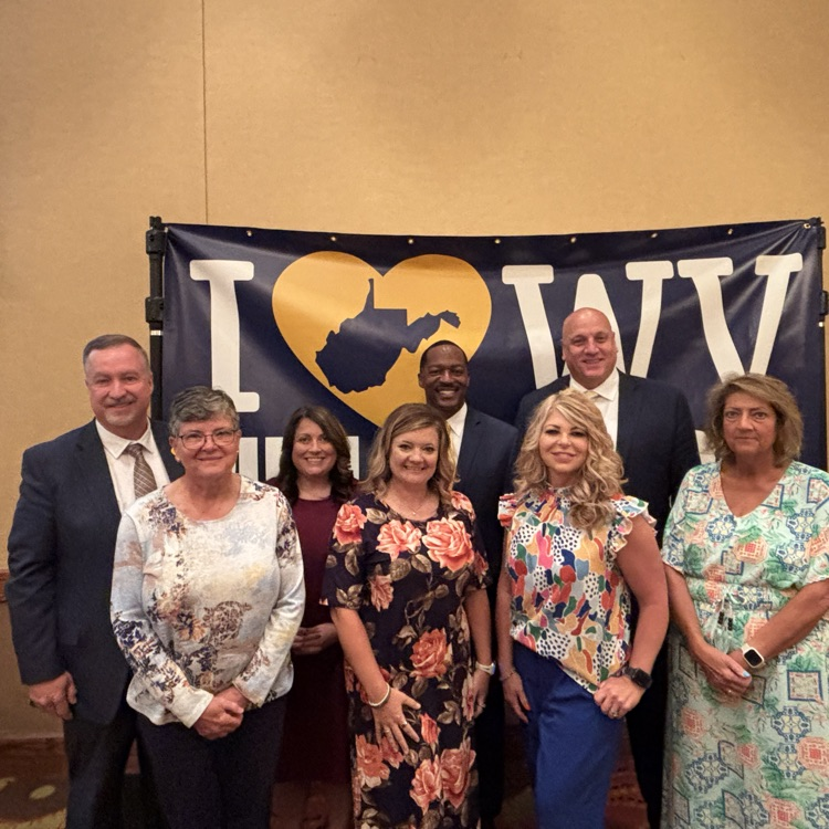 Group of people standing in front of an I love WV Public Schools banner