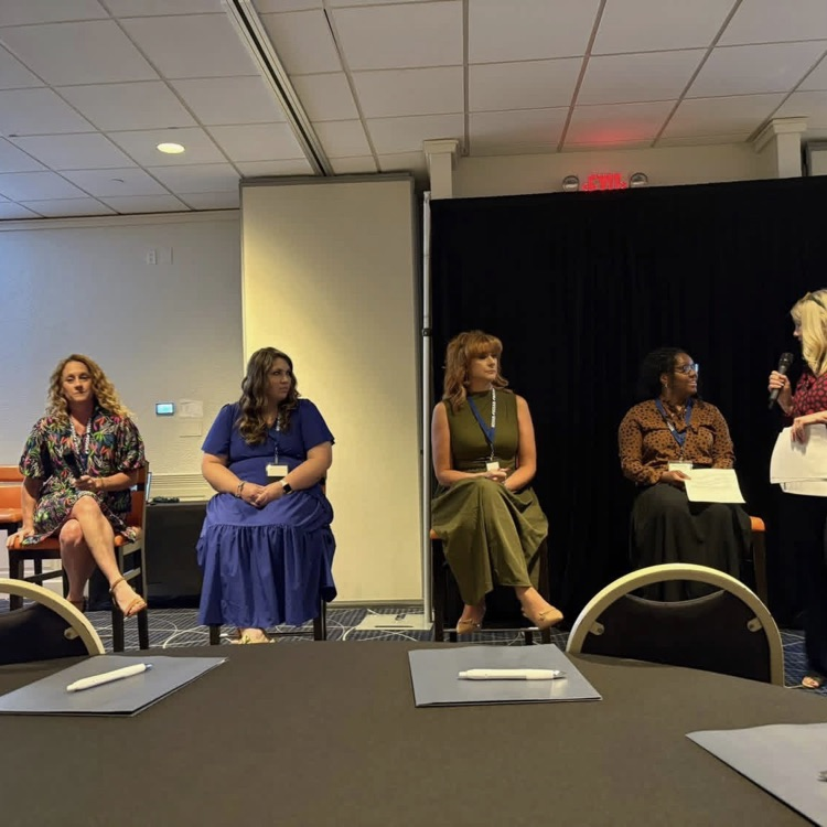 women on a stage in a conference room 