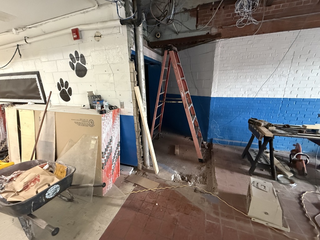 Interior of a room under construction. A ladder leans against the wall. Various materials and equipment are scattered around.