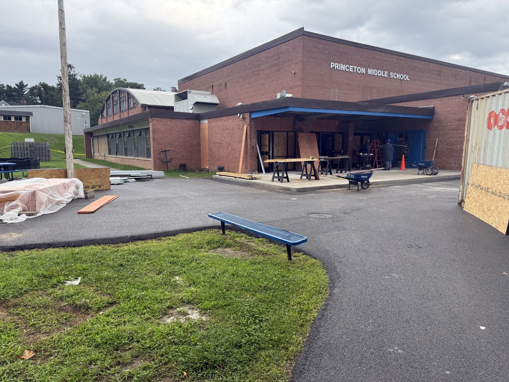 Building with "Princeton Middle School" sign. A bench on the left side. A construction site in front of the building.
