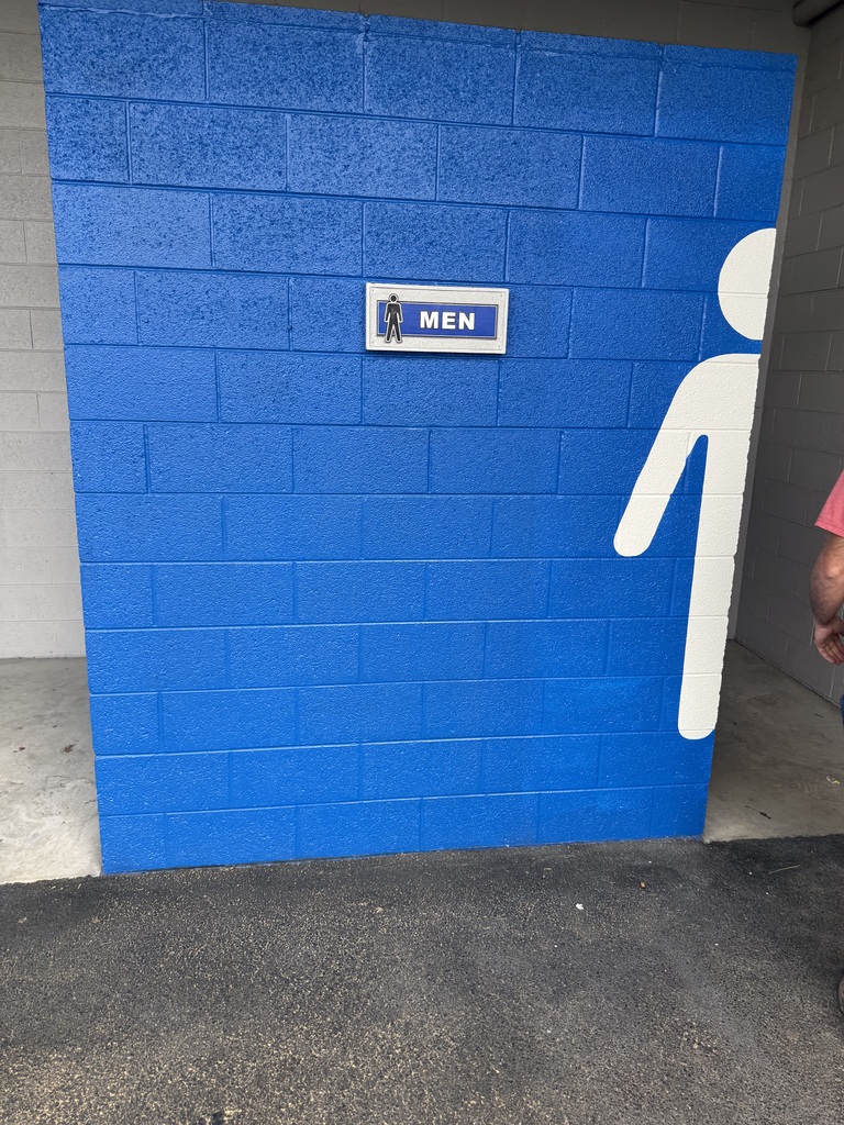 A blue brick wall with a white male icon and a label reading "MEN" on it.