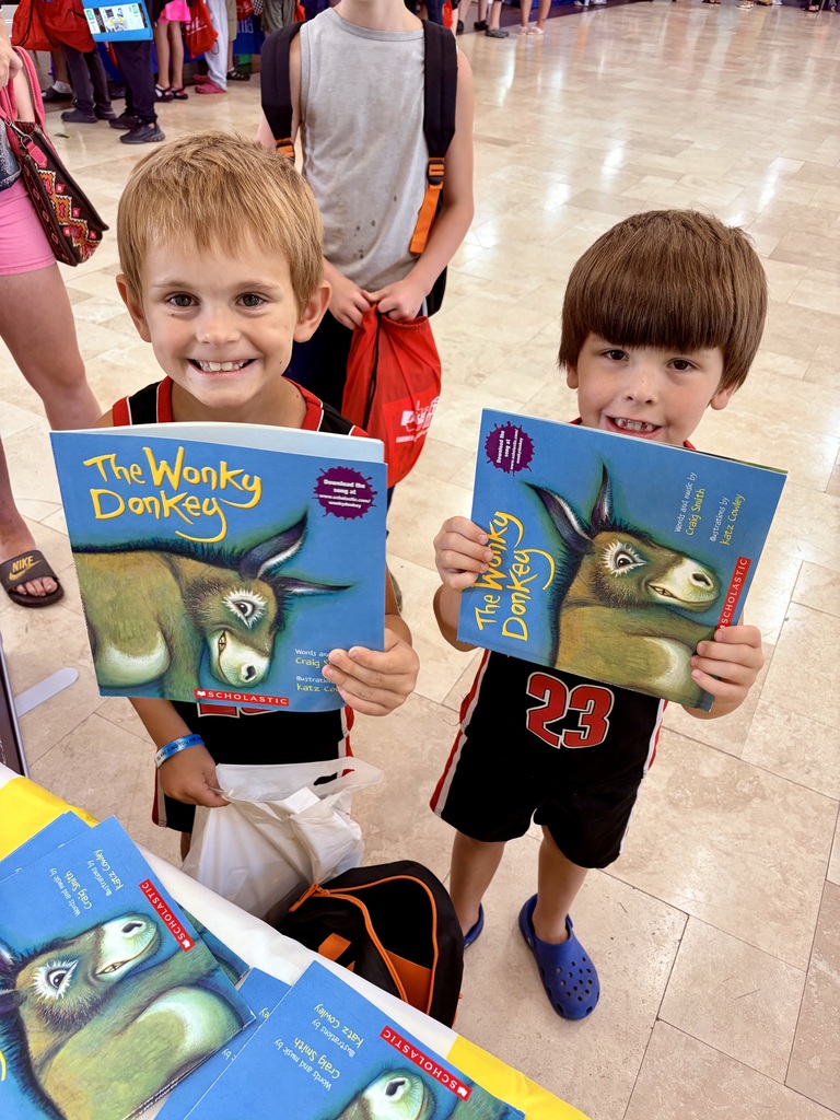 Two children showing a book titled The Wonky Donkey