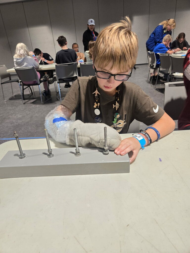 A child with a cast on one arm uses the other to manipulate rods on a table.