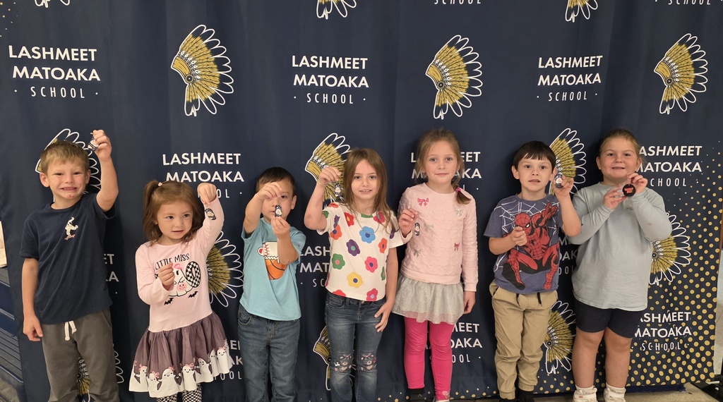 Group of young children posing for a photo in front of a blue banner with a logo.