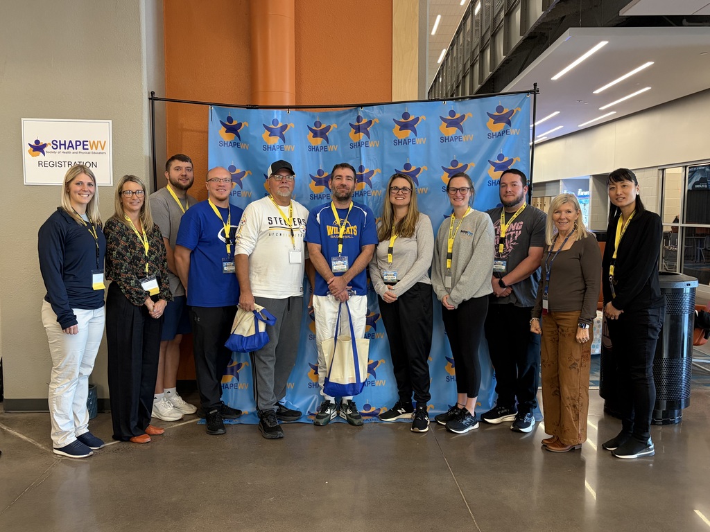 A group of teachers standing in front of a backdrop. They are attending a training for health and PE teachers