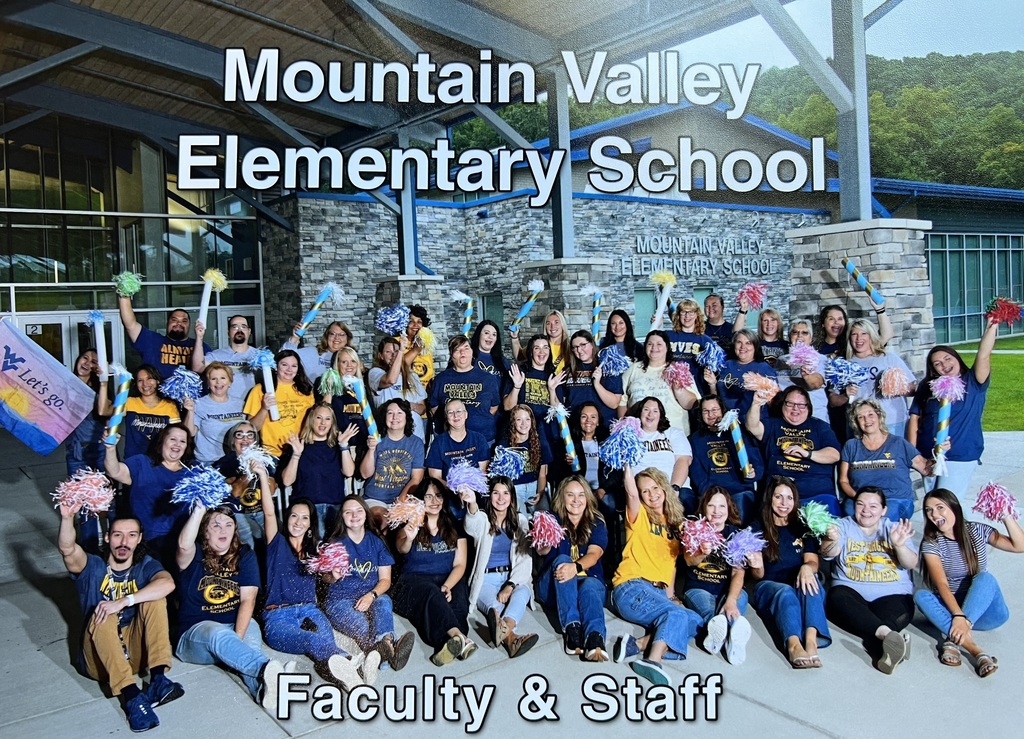 Faculty and staff in yellow and blue uniforms holding pom poms pose for a photo in front of a school.