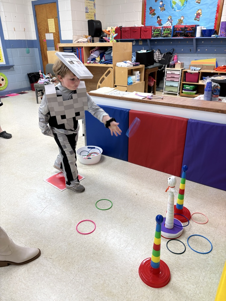 Child wearing costume, standing in a play area with rings and posts.