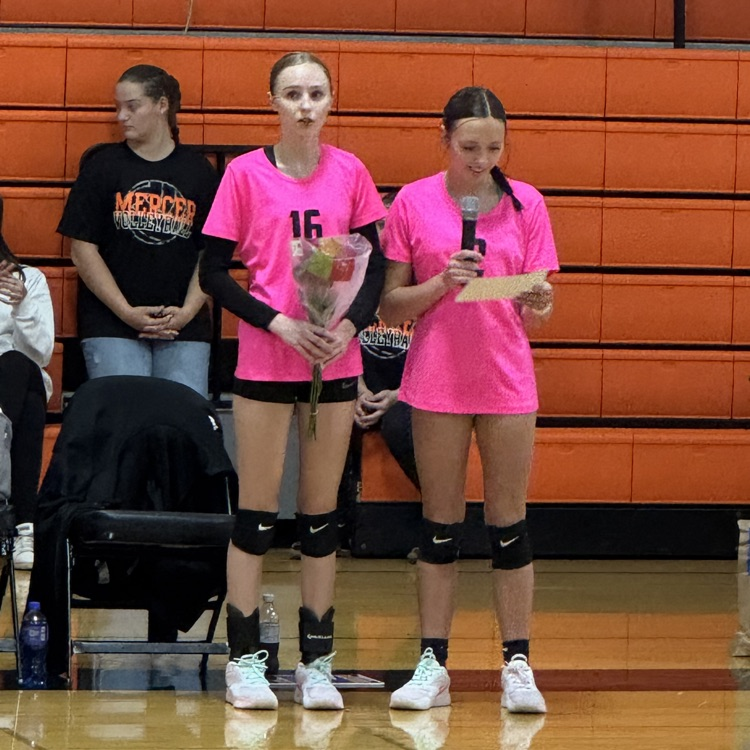 2 female volleyball players wearing pink shirt black shorts one on right with microphone