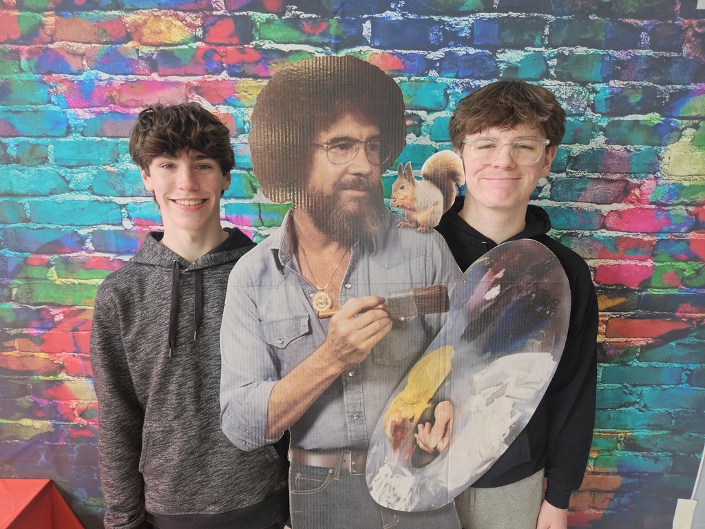 High school students Corbin Ouderkirk and Trent Beck pose with a life sized cut out of Bob Ross .