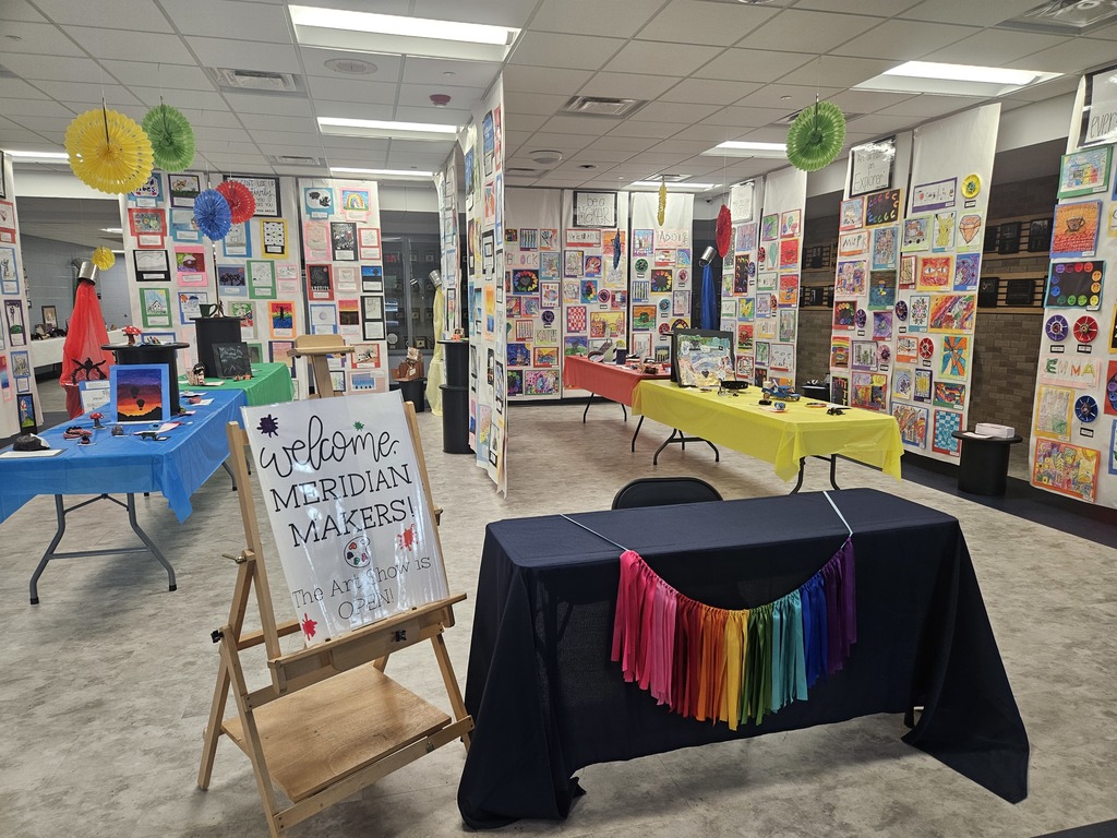 Photo showing the welcome table at Meridian's District Wide Art Show with a sign that reads, " Welcome Meridian Makers! The Art Show Is Open." 