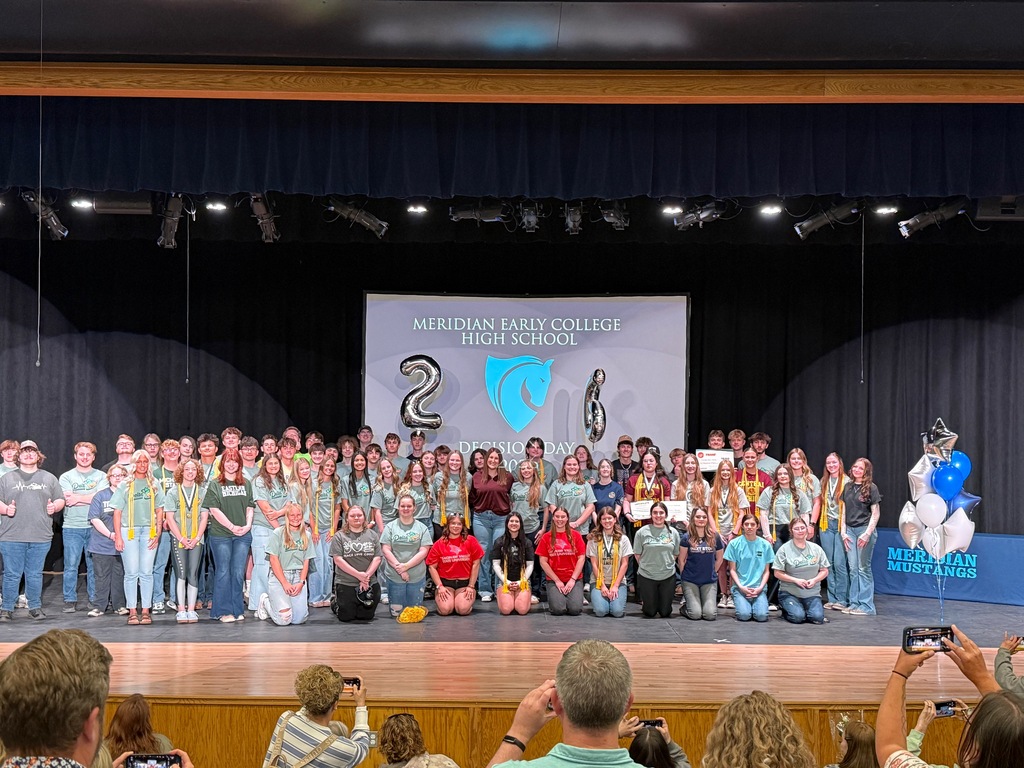 Students standing on a stage celebrating decision day at Meridian Early College High School