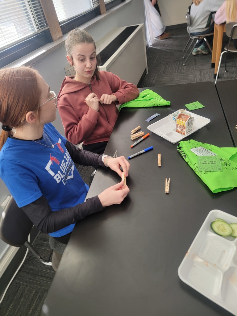 Two students sitting at a table with markers and clothes pins
