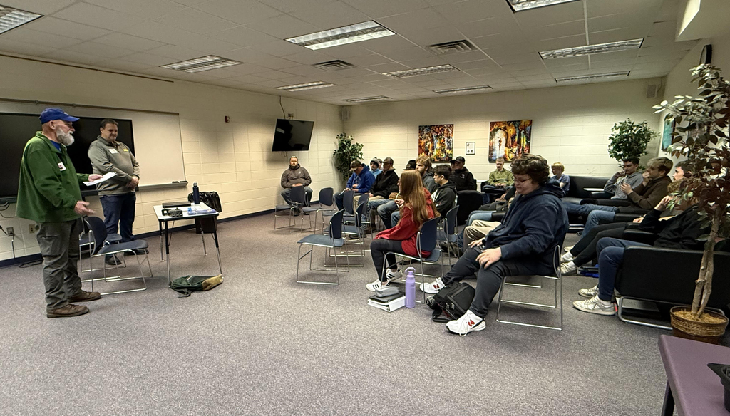 Two adults presenting to a class of students sitting on chairs