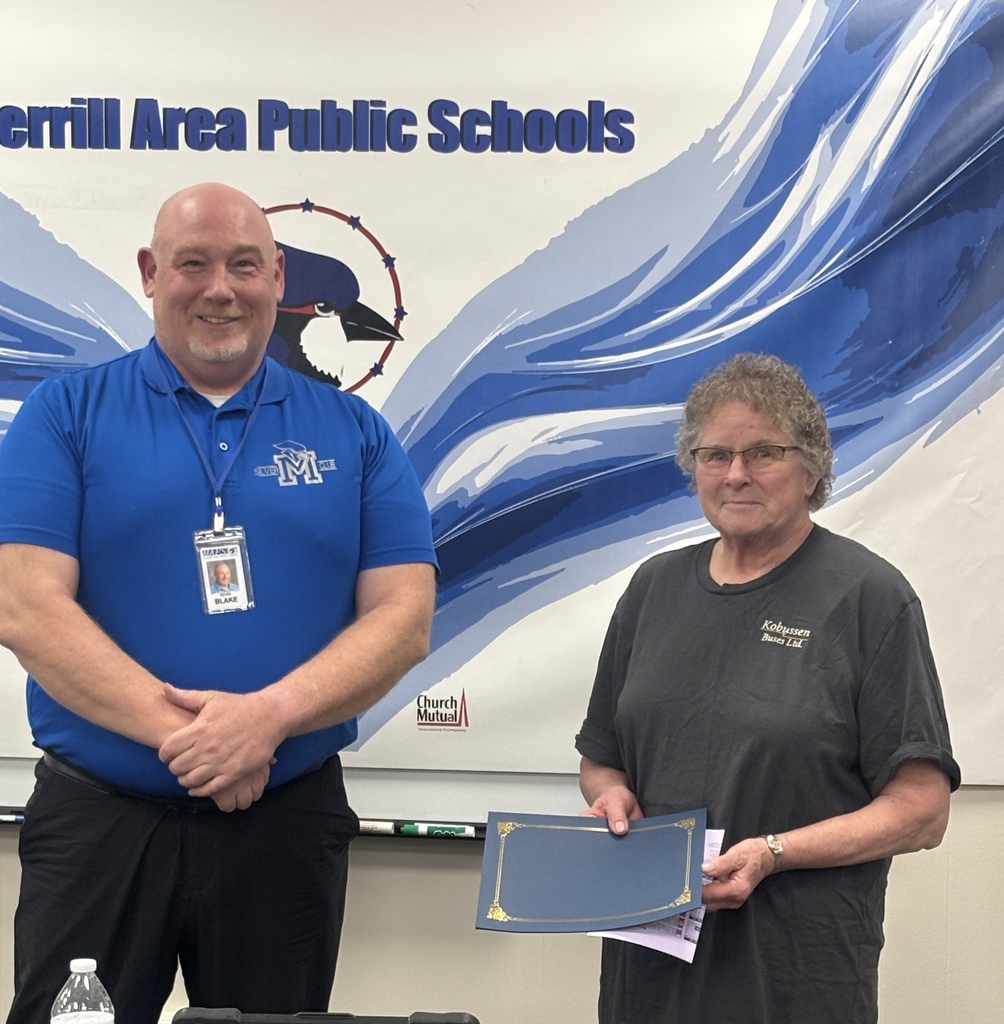 Mary Klade holding a certificate next to Board President Kevin Blake in front of a bluejay banner