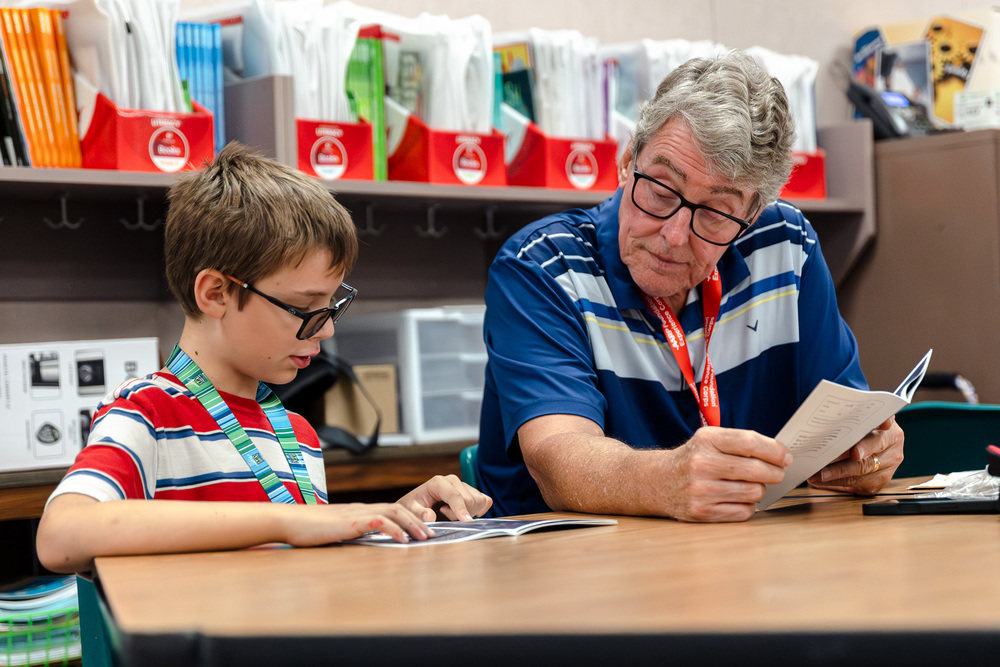 Volunteer tutors student as he reads